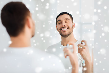 Image showing man with perfume looking to mirror at bathroom