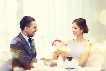 Image showing smiling man giving flower bouquet at restaurant