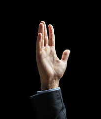 Image showing close up of raised businessman hand over black