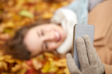 Image showing woman on autumn leaves taking selfie by smartphone