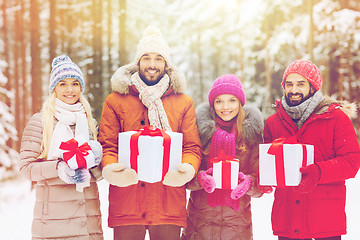 Image showing happy friends with gift boxes in winter forest