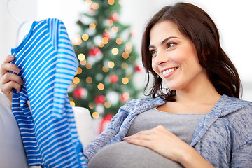 Image showing happy woman holding baby boys bodysuit at home