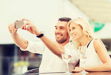 Image showing happy couple taking selfie with smartphone at cafe