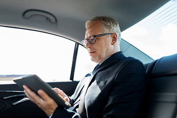 Image showing senior businessman with tablet pc driving in car