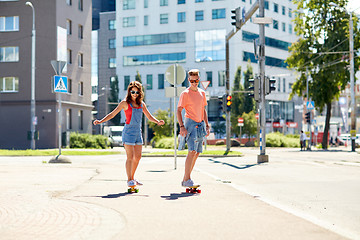 Image showing teenage couple riding skateboards on city street