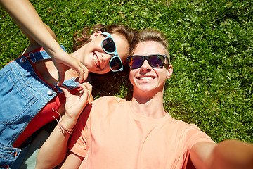 Image showing happy teenage couple taking selfie on summer grass