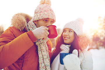 Image showing happy couple with tea cups over winter landscape