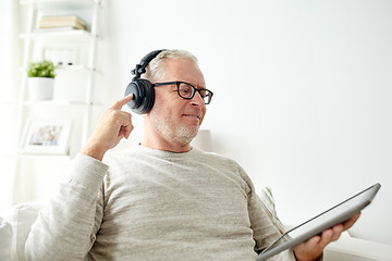 Image showing senior man with tablet pc and headphones at home