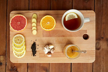 Image showing ginger tea with honey, citrus and garlic on wood