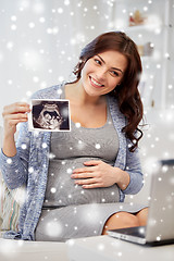 Image showing happy pregnant woman with ultrasound image at home