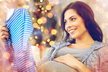 Image showing happy woman holding baby boys bodysuit at home