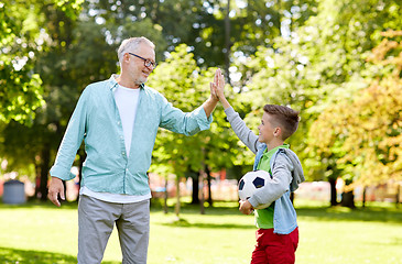 Image showing old man and boy with soccer ball making high five