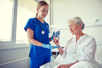 Image showing nurse giving medicine to senior woman at hospital