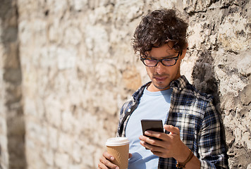 Image showing man with smartphone drinking coffee on city street