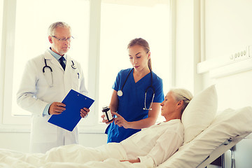 Image showing doctor giving medicine to senior woman at hospital