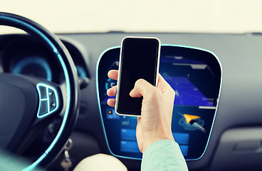 Image showing close up of male hand with smartphone driving car