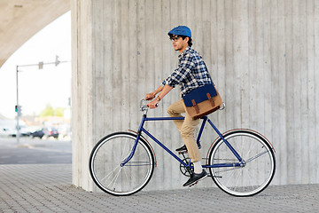 Image showing young hipster man with bag riding fixed gear bike