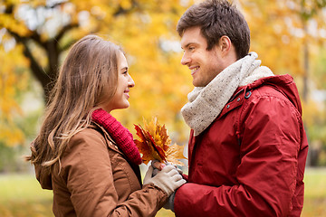 Image showing happy couple with maple leaves in autumn park