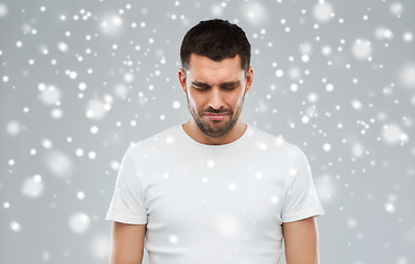 Image showing unhappy young man over snow background