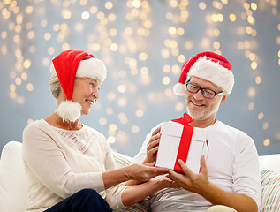 Image showing happy senior couple in santa hats with gift box