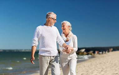 Image showing happy senior couple holding hands on summer beach