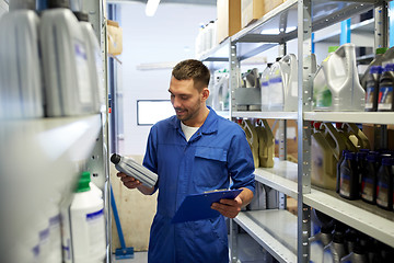 Image showing auto mechanic with oil and clipboard at car shop