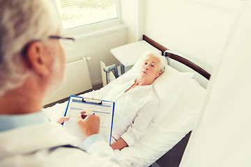 Image showing senior woman and doctor with clipboard at hospital