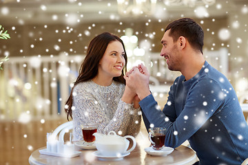 Image showing happy couple with tea holding hands at restaurant