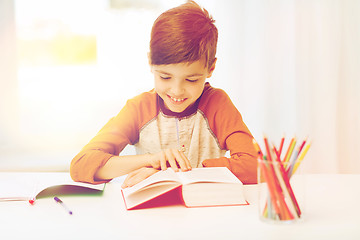Image showing smiling, student boy reading book at home