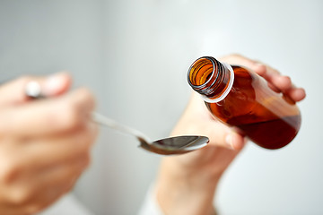 Image showing woman pouring medication from bottle to spoon