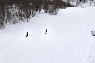 Image showing Skier and snowboarder on ski slope at gray winter day