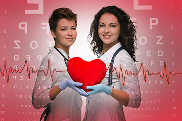 Image showing Two woman doctor holding a red heart