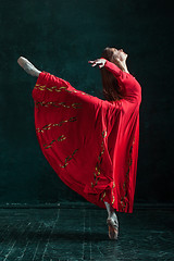 Image showing Ballerina posing in pointe shoes at black wooden pavilion