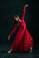 Image showing Ballerina posing in pointe shoes at black wooden pavilion