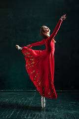 Image showing Ballerina posing in pointe shoes at black wooden pavilion