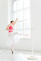 Image showing Ballerina posing in pointe shoes at white wooden pavilion