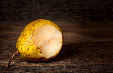 Image showing One bitten pear lying on a wooden table
