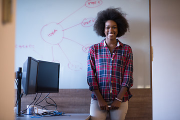 Image showing African American woman writing on a chalkboard in a modern offic