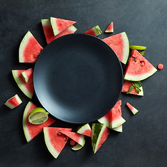 Image showing slices of watermelon placed in a circle on black plate