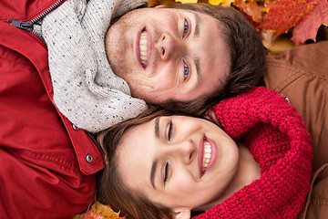 Image showing close up of smiling couple lying on autumn leaves