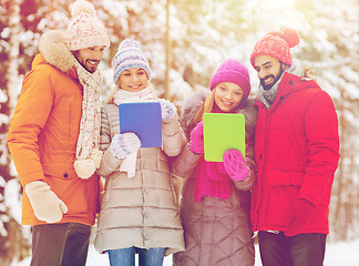 Image showing smiling friends with tablet pc in winter forest