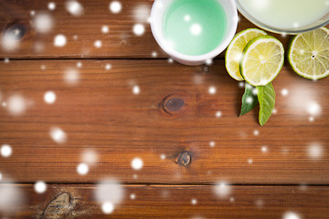 Image showing body lotion, cream and limes on wood