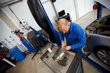 Image showing mechanic man with wrench repairing car at workshop