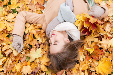 Image showing beautiful happy woman lying on autumn leaves