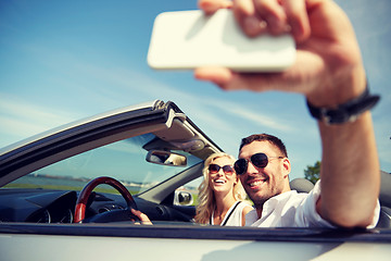 Image showing happy couple in car taking selfie with smartphone