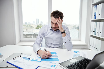 Image showing stressed businessman with papers in office