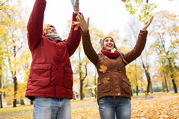 Image showing happy young couple throwing autumn leaves in park