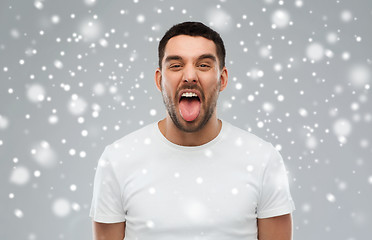 Image showing man showing his tongue over snow background