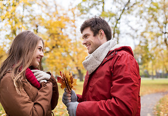 Image showing happy couple with maple leaves in autumn park