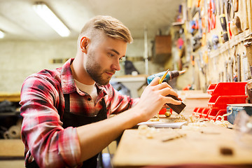 Image showing carpenter working with wood plank at workshop